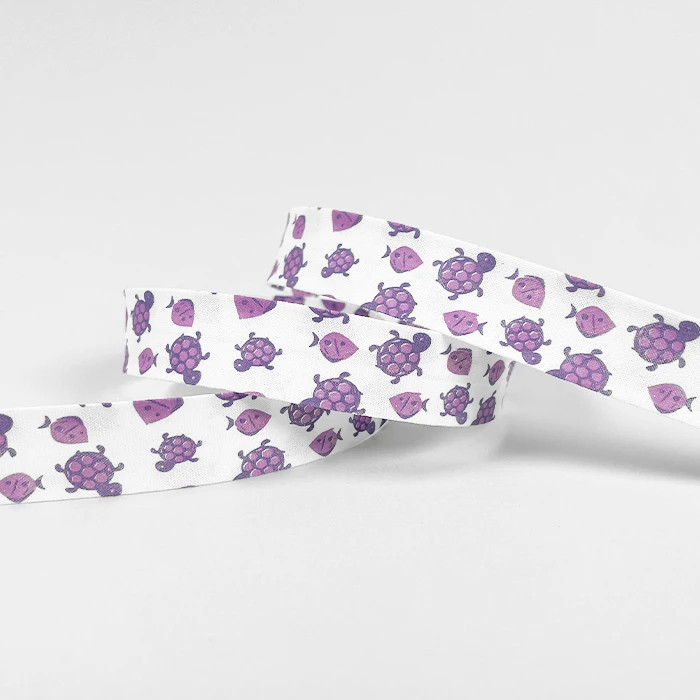 Biais replié 20mm blanc motif tortues et poissons mauves /m Biais replié 20mm blanc motif tortues et poissons mauves /m